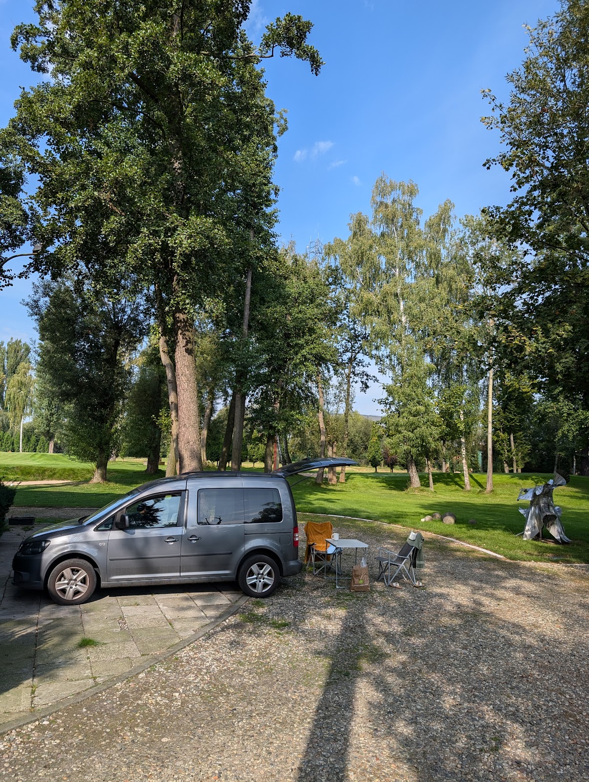 Lekcja gry w golfa na polu Arkadia - trener pokazuje ustawienie do uderzenia, kursant z kijem, równa trawa, spokojne otoczenie